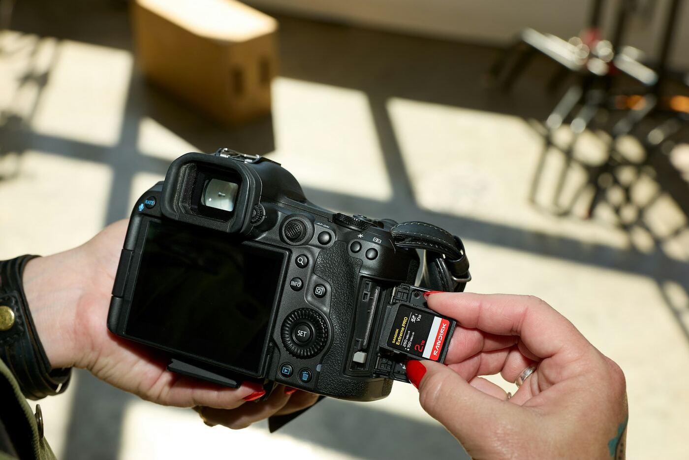 Someone sliding an SD card into the side of a mirrorless camera